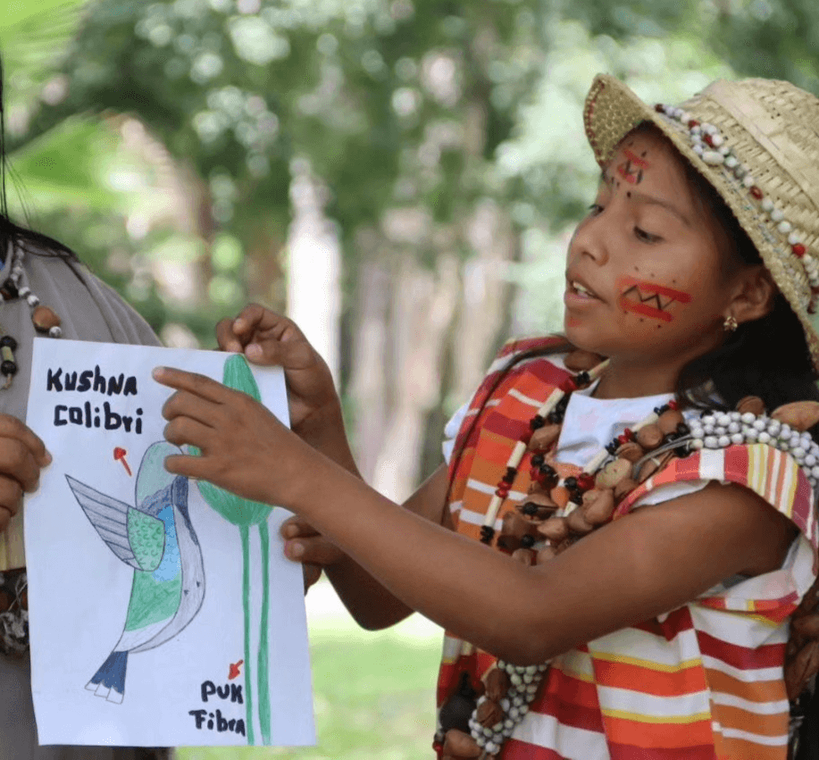 Niña Yukpa mostrando un dibujo de un colibrí (kushna) con su nombre en Yukpa